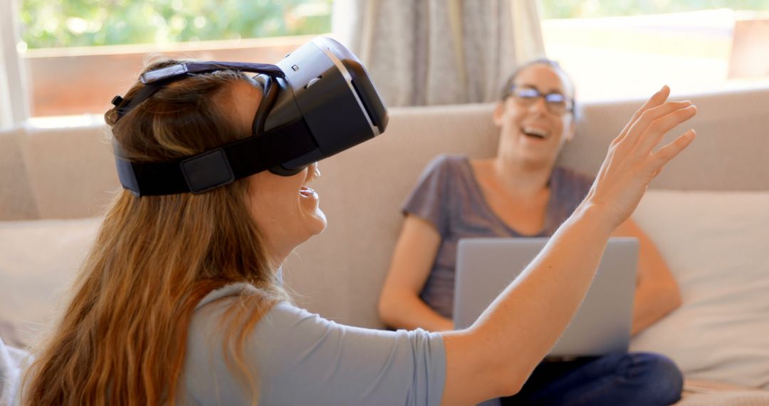 Woman Using Virtual Reality Headset with Friend Laughing on Sofa - Free Images, Stock Photos and Pictures on Pikwizard.com