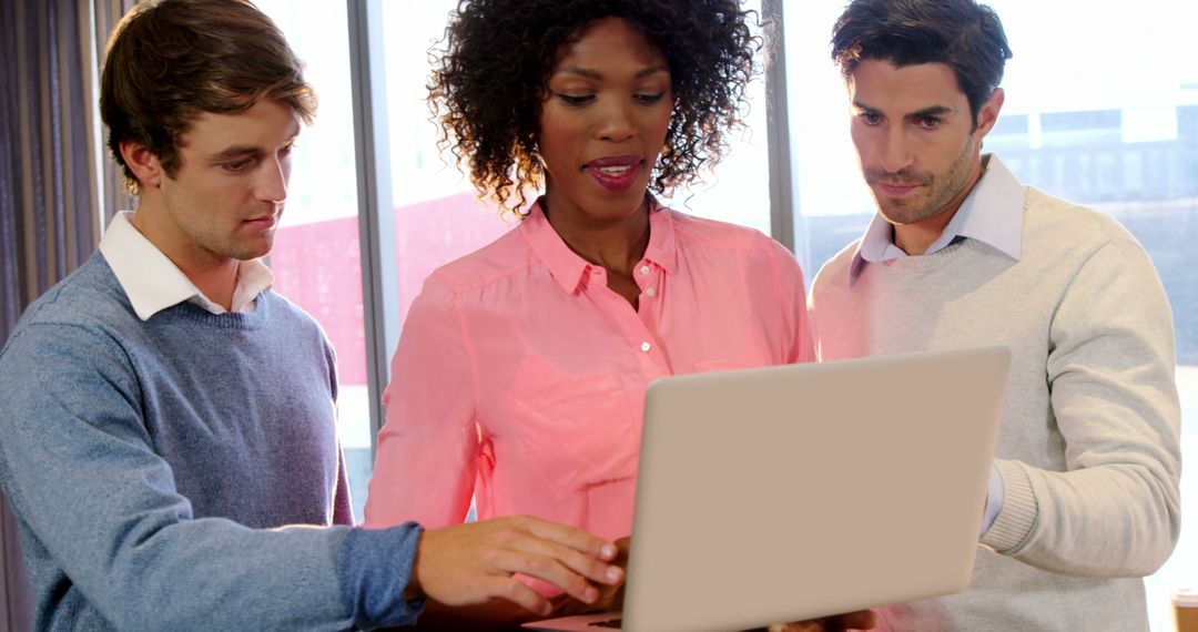 Diverse Team Collaborating on a Laptop in Modern Office
