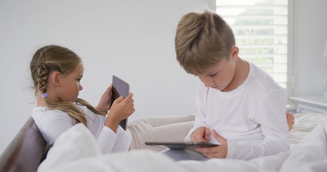 Kids Using Tablets while Sitting on a Bed in Well-Lit Room - Free Images, Stock Photos and Pictures on Pikwizard.com