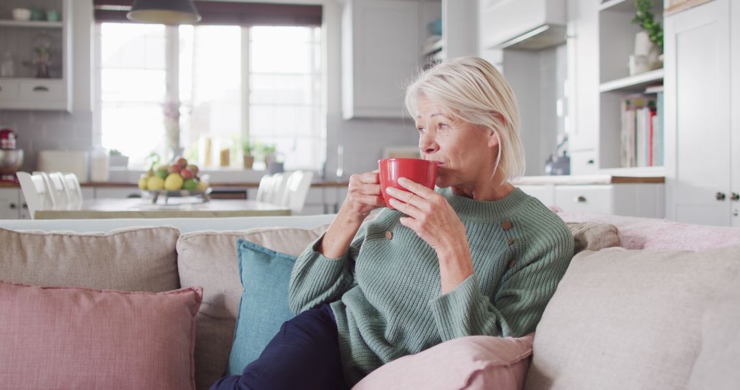 Senior woman relaxing on sofa with coffee cup in cozy home - Free Images, Stock Photos and Pictures on Pikwizard.com