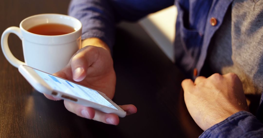 Person Using Smartphone While Drinking Tea Indoors - Free Images, Stock Photos and Pictures on Pikwizard.com