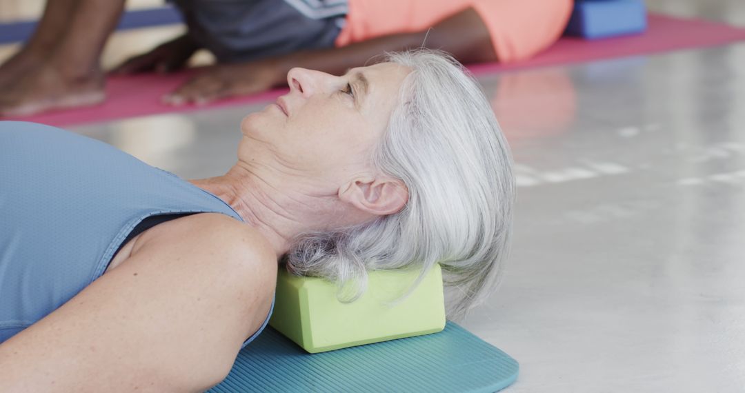 Senior Woman Relaxing on Yoga Block During Exercise Class - Free Images, Stock Photos and Pictures on Pikwizard.com