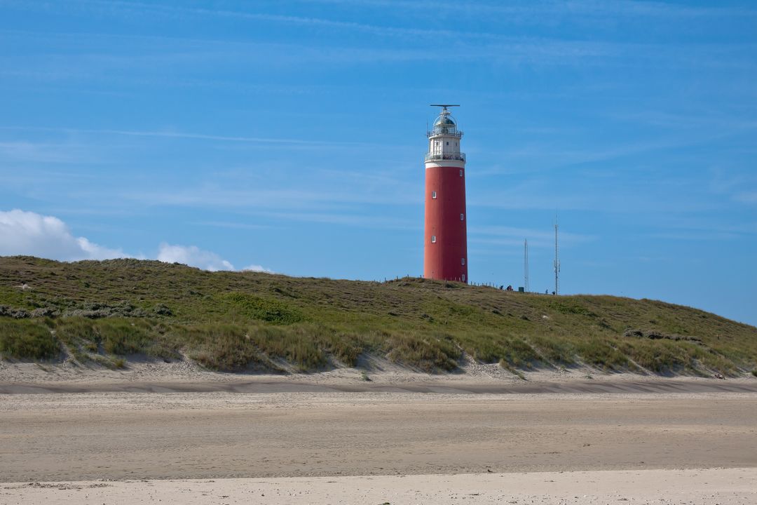 Red Lighthouse on Sandy Beach Under Blue Sky - Free Images, Stock Photos and Pictures on Pikwizard.com