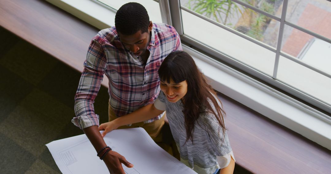 Collaborative Team Reviewing Blueprint in Modern Office