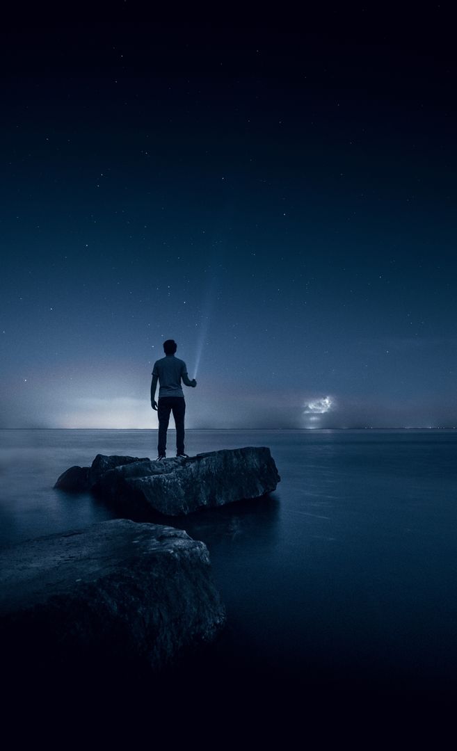 Man Gazing at Night Sky on Rocks by Ocean