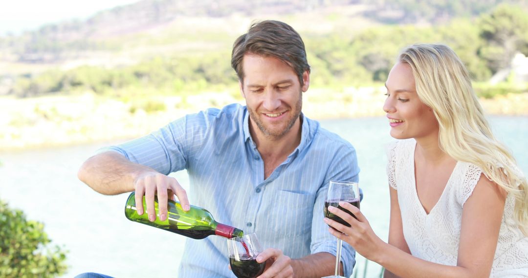 Couple Enjoying Wine Outdoors by Scenic Lake - Free Images, Stock Photos and Pictures on Pikwizard.com