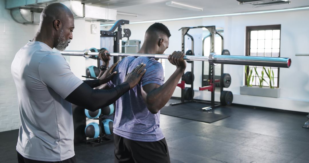 Personal Trainer Guiding Client in Barbell Squat Exercise at Gym