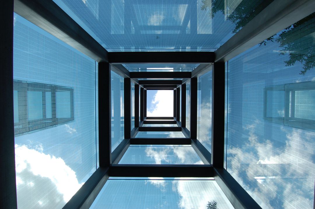 Futuristic glass walkway framed by metal beams with a view of blue sky and clouds - Free Images, Stock Photos and Pictures on Pikwizard.com