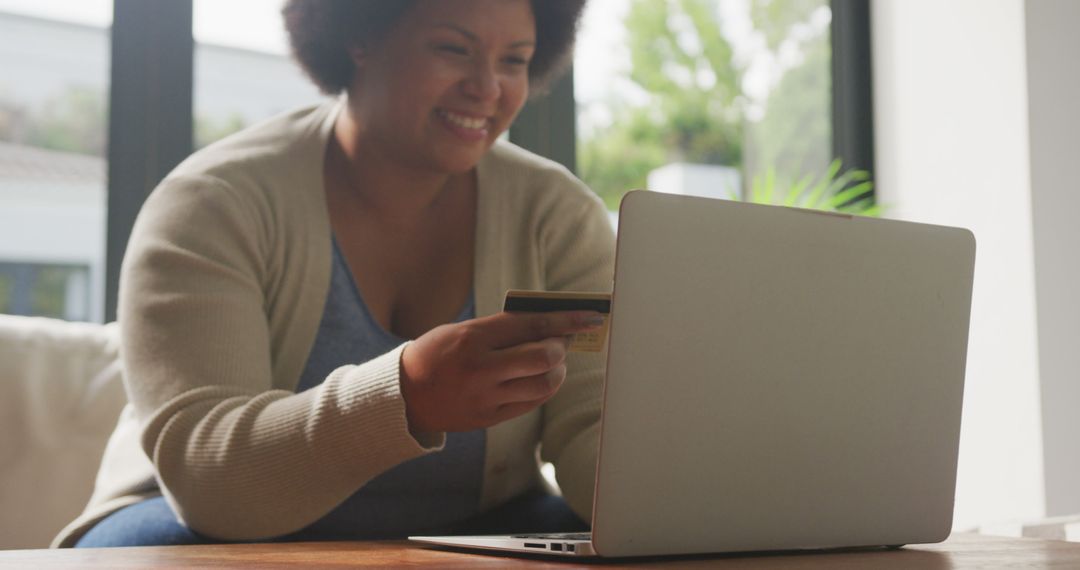 Image of happy plus size african american woman holding credit card and using laptop - Free Images, Stock Photos and Pictures on Pikwizard.com