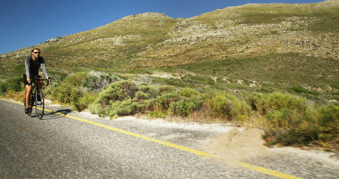 Cyclist Riding Mountain Road on Sunny Day - Free Images, Stock Photos and Pictures on Pikwizard.com