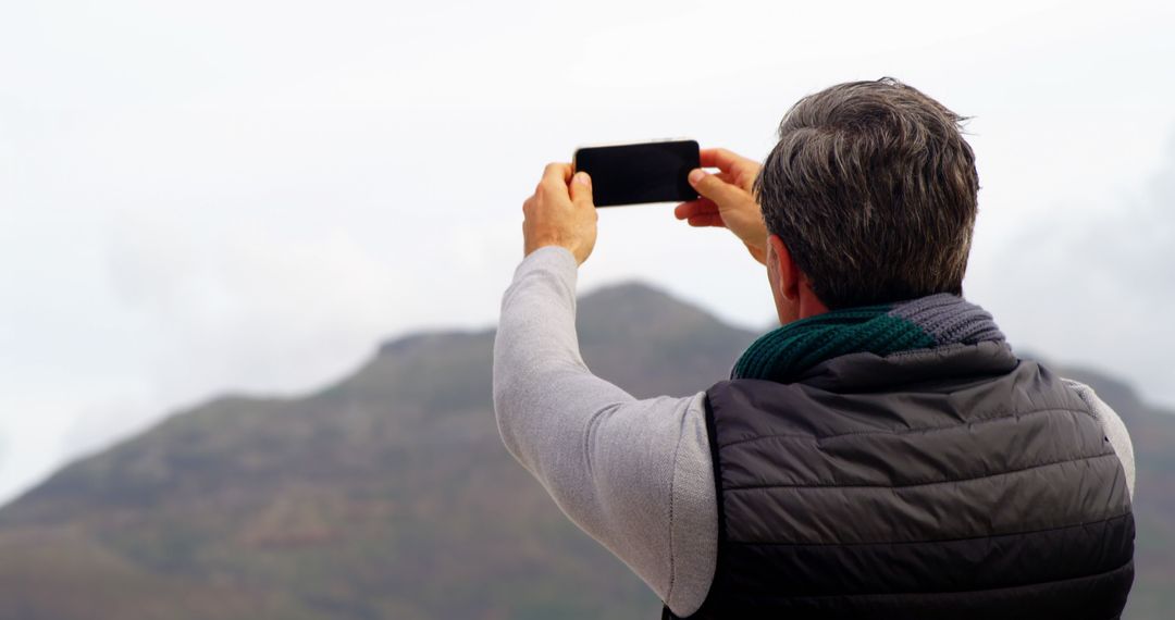 Man Taking Photo with Smartphone Against Mountain Landscape - Free Images, Stock Photos and Pictures on Pikwizard.com