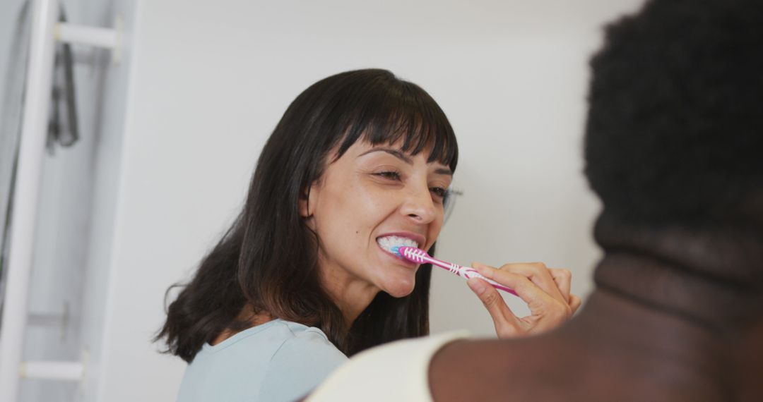 Smiling Woman Brushing Teeth in Modern Bathroom - Free Images, Stock Photos and Pictures on Pikwizard.com