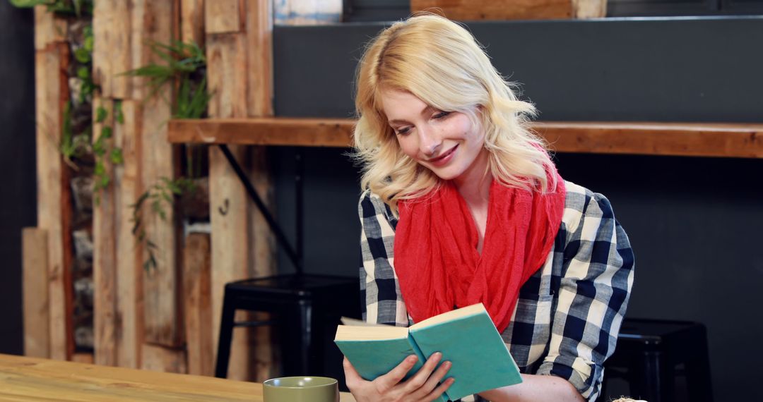 Blonde woman reading book in cafe, red scarf - Free Images, Stock Photos and Pictures on Pikwizard.com