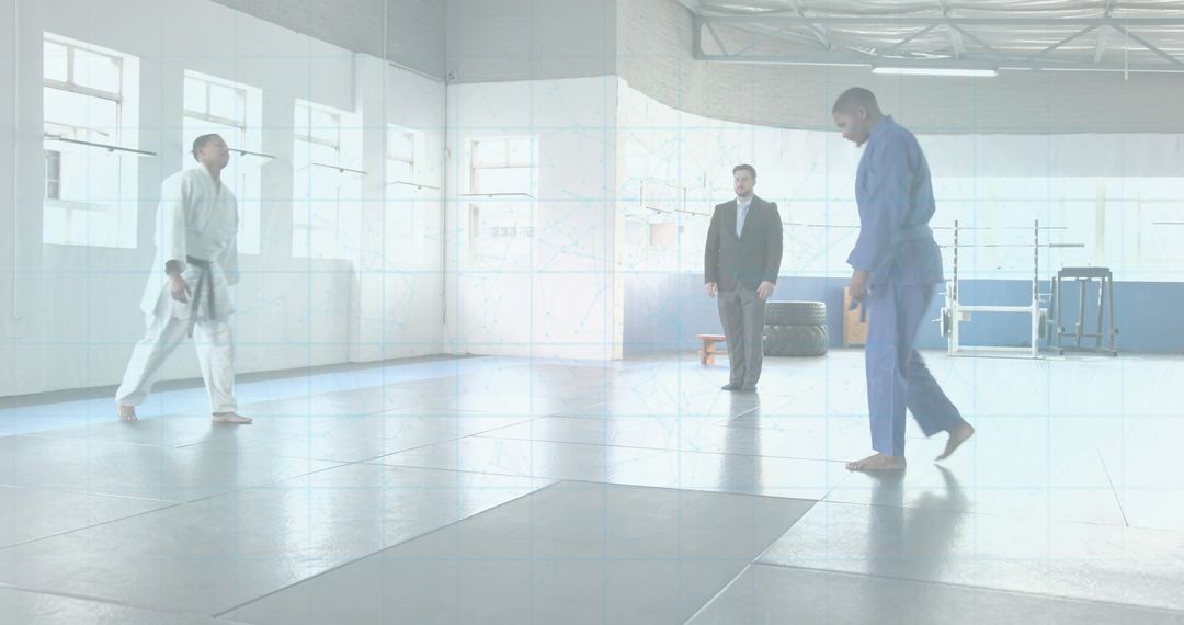 Gi Fighters Walking to Center Mat While Referee Observing in Bright Martial Arts Gym