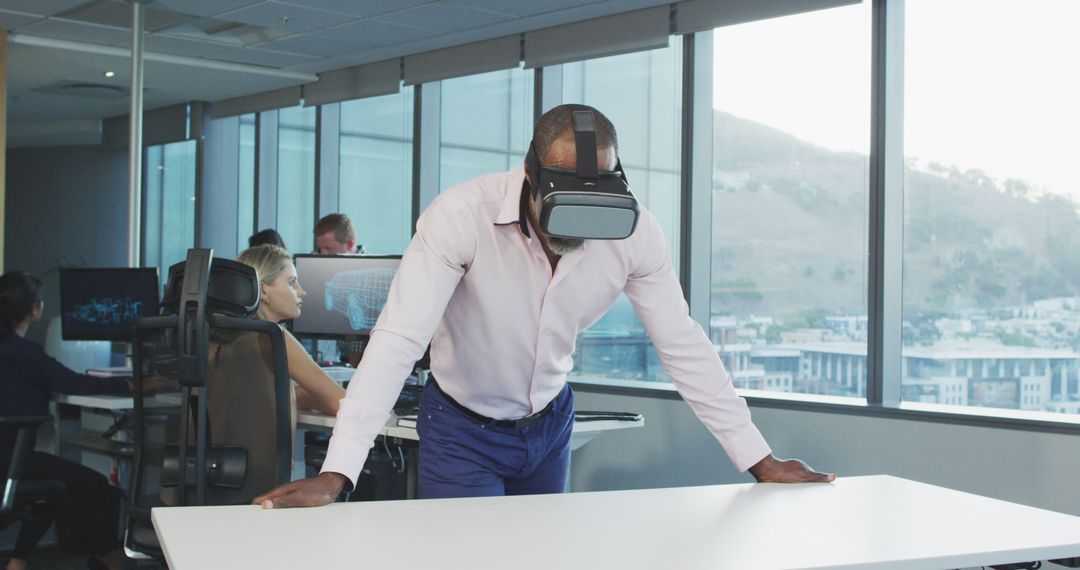 African american businessman using vr headset, with colleagues using computers at office - Free Images, Stock Photos and Pictures on Pikwizard.com