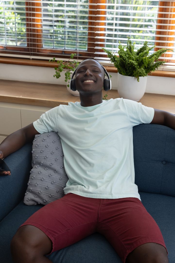 Joyful Young Man Relaxing with Wireless Headphones at Home