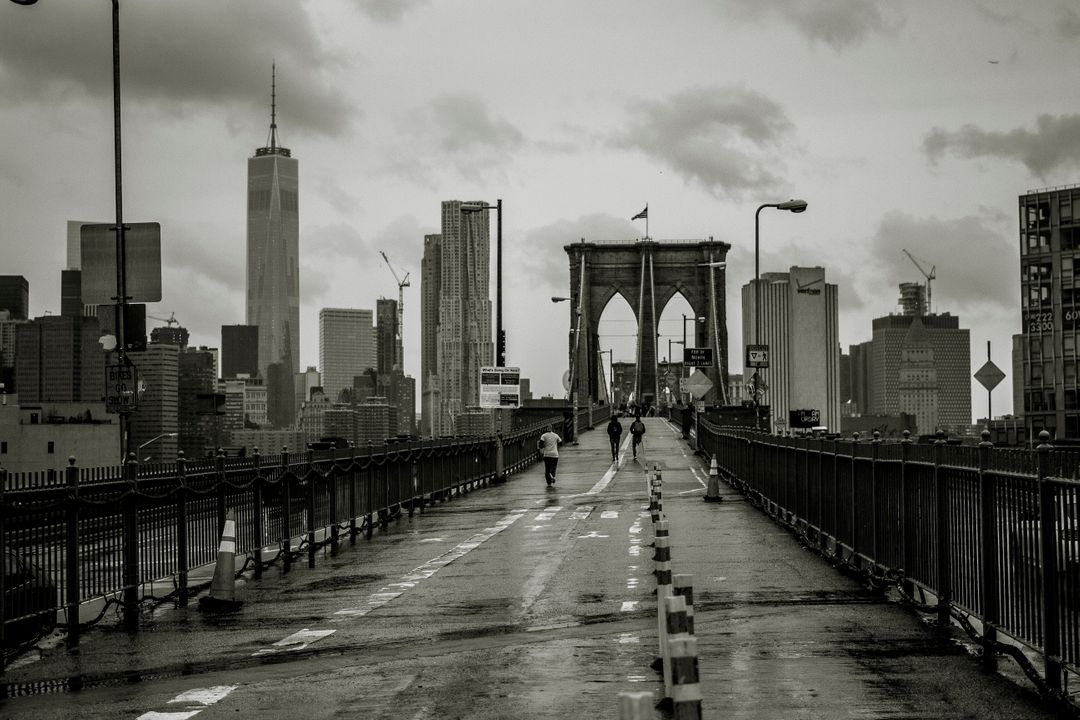 People Walking on Rainy Brooklyn Bridge with NYC Skyline in Background - Free Images, Stock Photos and Pictures on Pikwizard.com
