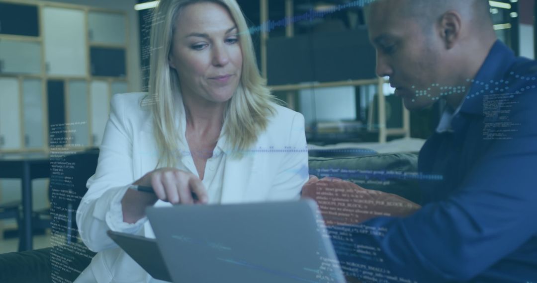 Coworkers Analyzing Data on Laptop in Modern Office Environment