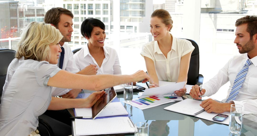 Diverse business team discussing charts around conference table in modern office - Free Images, Stock Photos and Pictures on Pikwizard.com