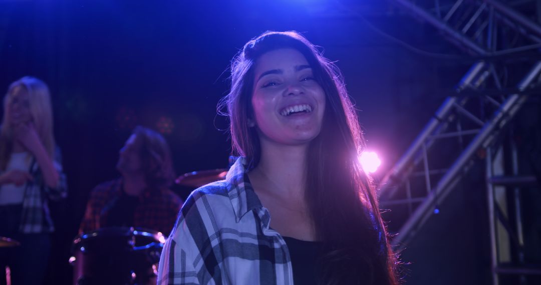 Smiling Female Musician with Band at Rehearsal in Vibrant Lighting
