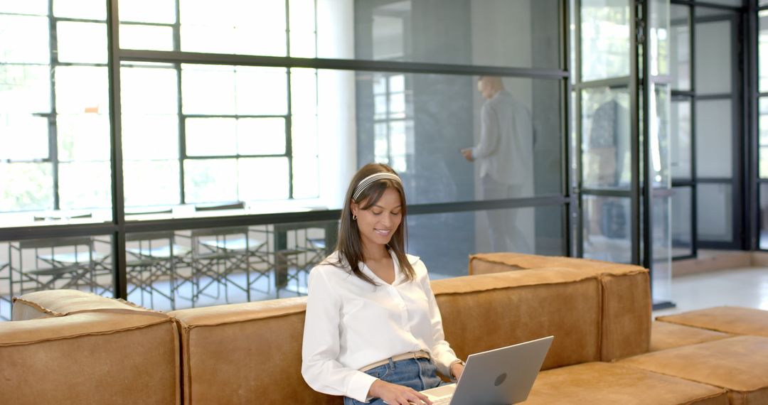 Businesswoman Using Laptop on Couch in Modern Office