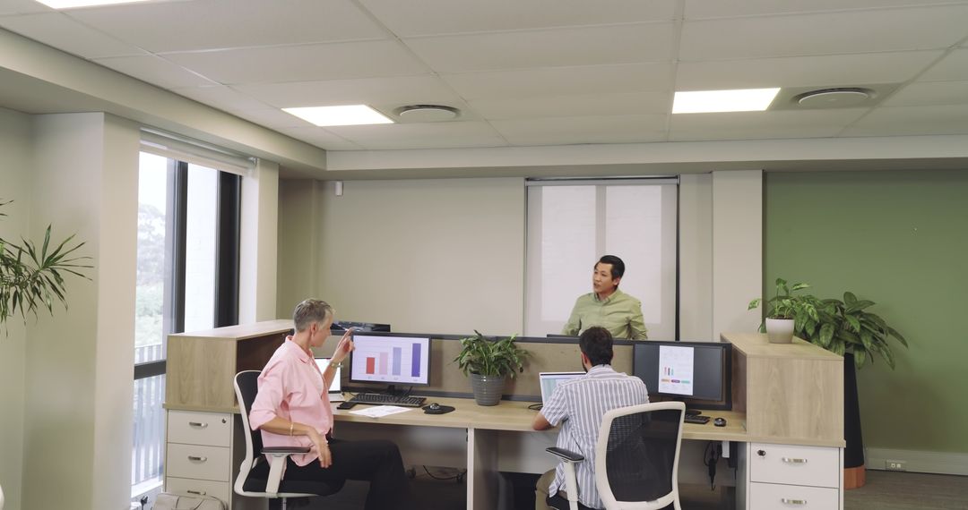 Diverse Team Working with Data on Dual Monitors in Modern Office