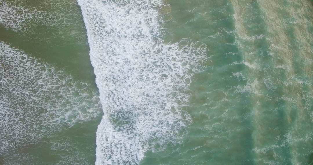 Aerial View of Transparent Ocean Waves Crashing on Shoreline