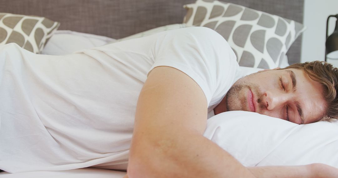 Young man sleeping peacefully on white pillow in cozy bed - Free Images, Stock Photos and Pictures on Pikwizard.com