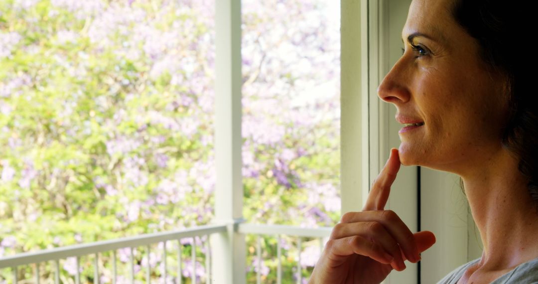 Smiling Woman Standing by Window Enjoying Spring View - Free Images, Stock Photos and Pictures on Pikwizard.com