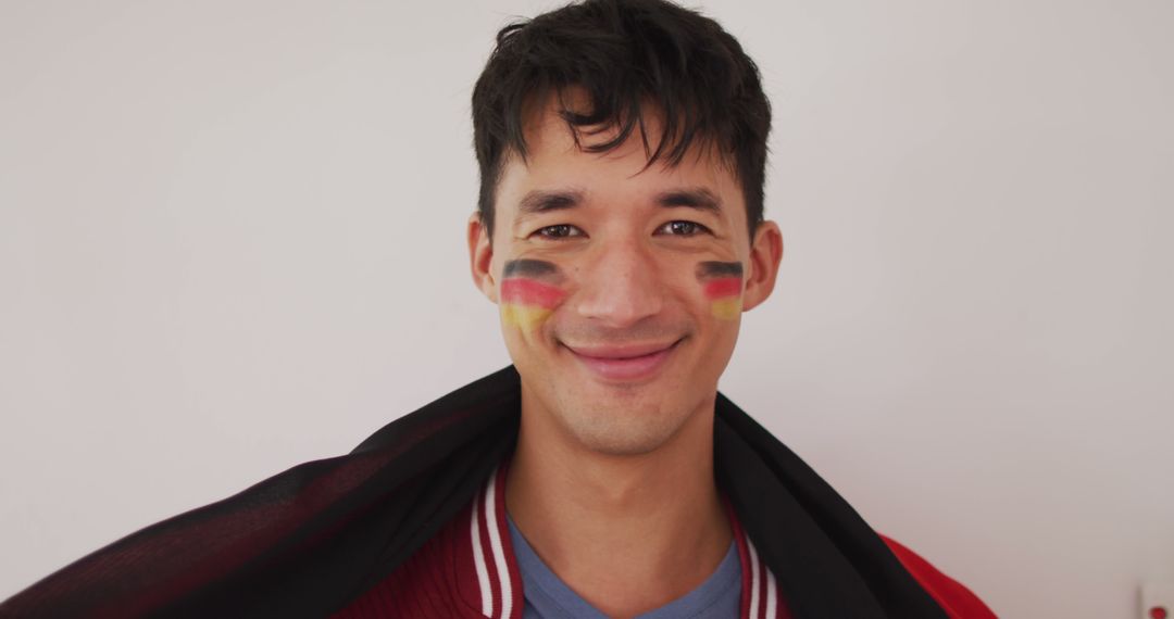 Portrait of happy biracial man with national flag and flag of germany on cheek - Free Images, Stock Photos and Pictures on Pikwizard.com