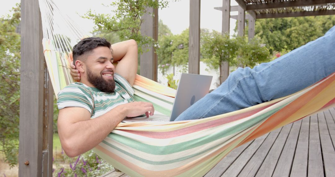 Man Relaxing with Laptop in Hammock on Wooden Deck