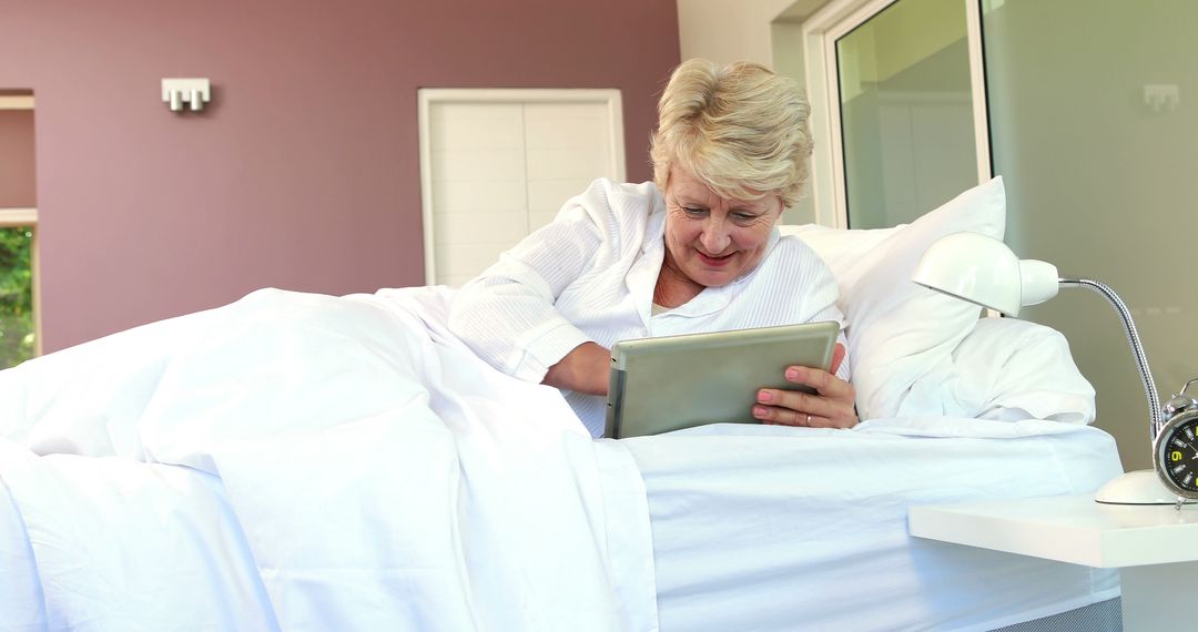 Smiling Senior Woman Using Tablet in Bed at Home - Free Images, Stock Photos and Pictures on Pikwizard.com