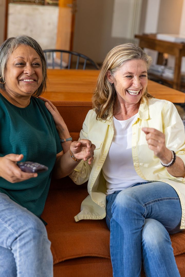 Senior Female Friends Laughing on Comfortable Sofa at Home