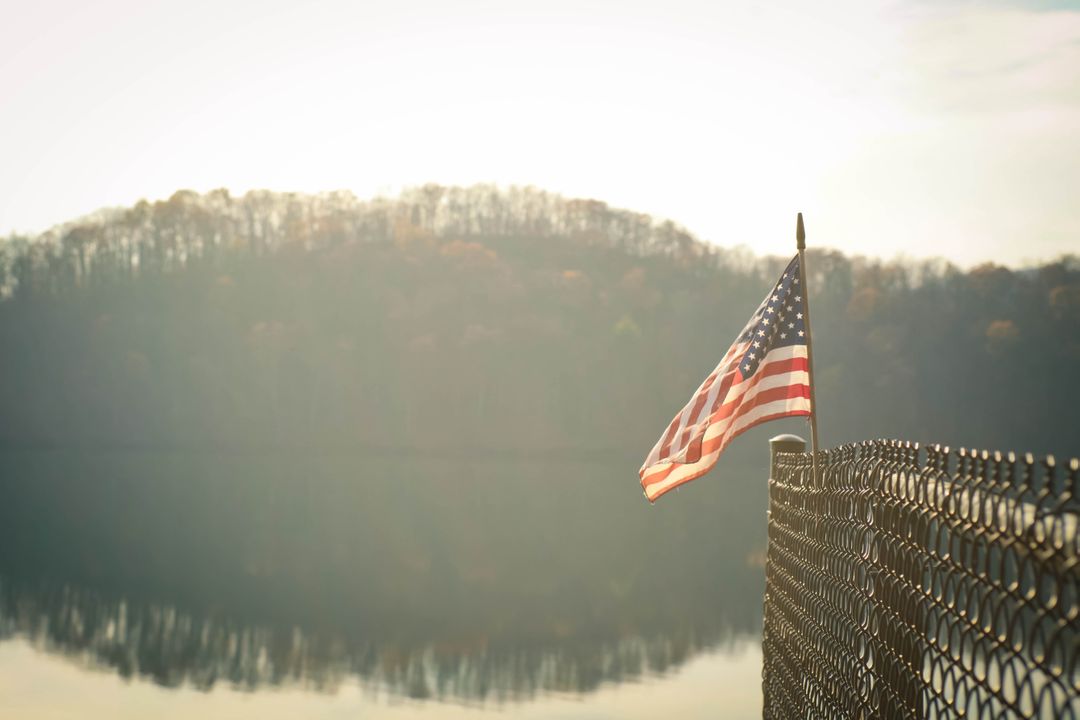 American Flag on Fence by Tranquil Lake at Sunrise - Free Images, Stock Photos and Pictures on Pikwizard.com