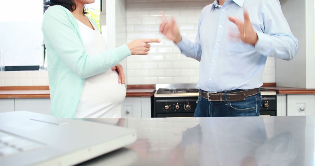 Expectant Couple Engaged in Dynamic Dialogue in Modern Kitchen