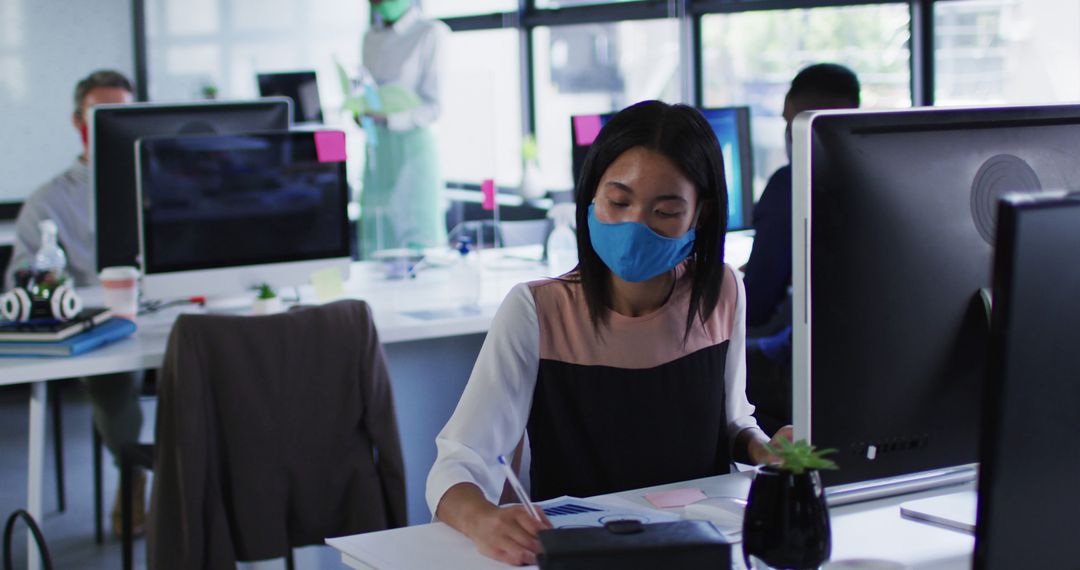 Office workers wearing masks during pandemic sit at desks - Free Images, Stock Photos and Pictures on Pikwizard.com