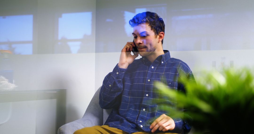 Young Man Talking on Phone in Modern Office with Blue Reflection - Free Images, Stock Photos and Pictures on Pikwizard.com