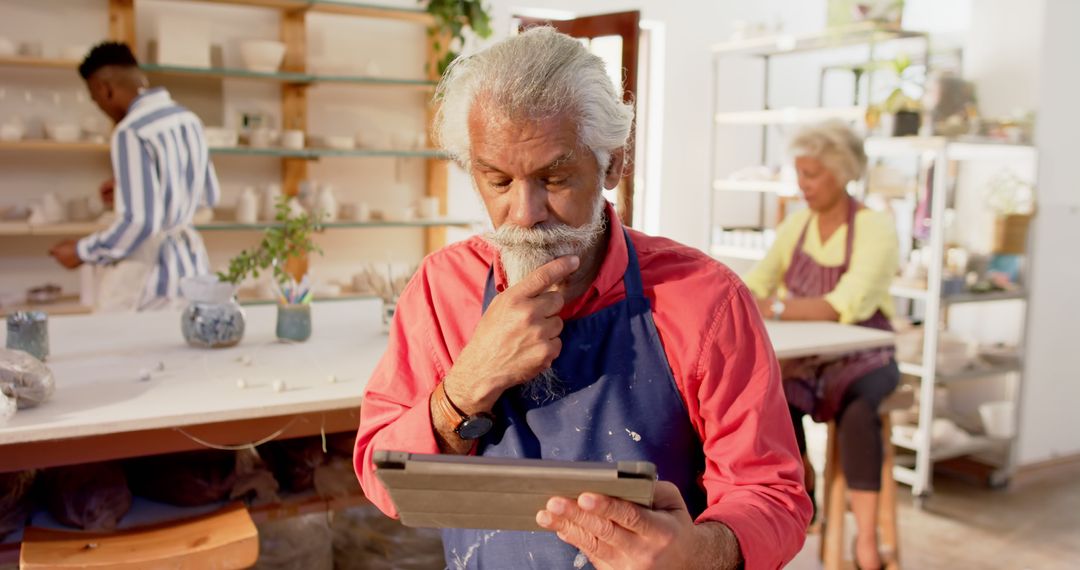 Senior Male Artisan Using Tablet in Pottery Workshop - Free Images, Stock Photos and Pictures on Pikwizard.com