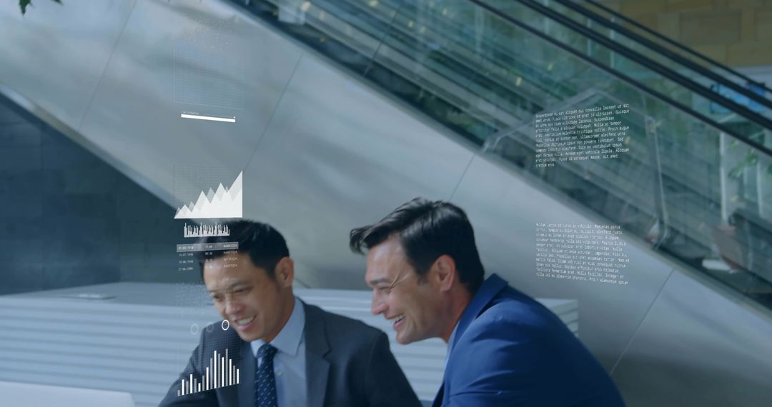 Business colleagues collaborating over laptop with holographic data charts in modern atrium