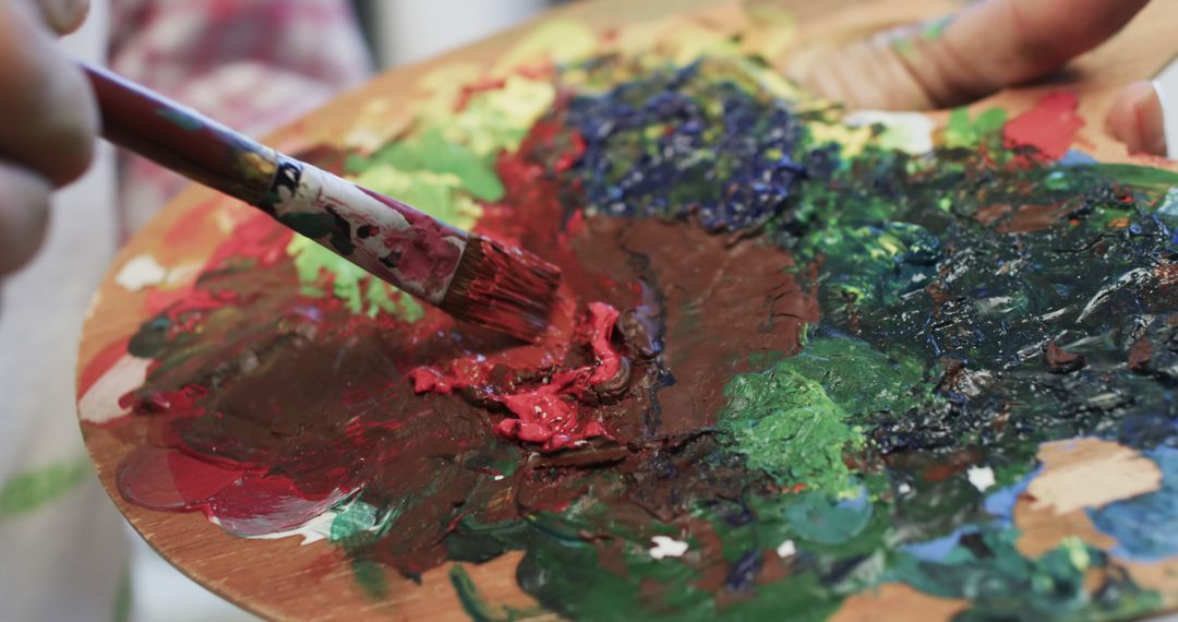 A biracial female artist mixes paints on a palette in her studio, embodying creative life. - Free Images, Stock Photos and Pictures on Pikwizard.com