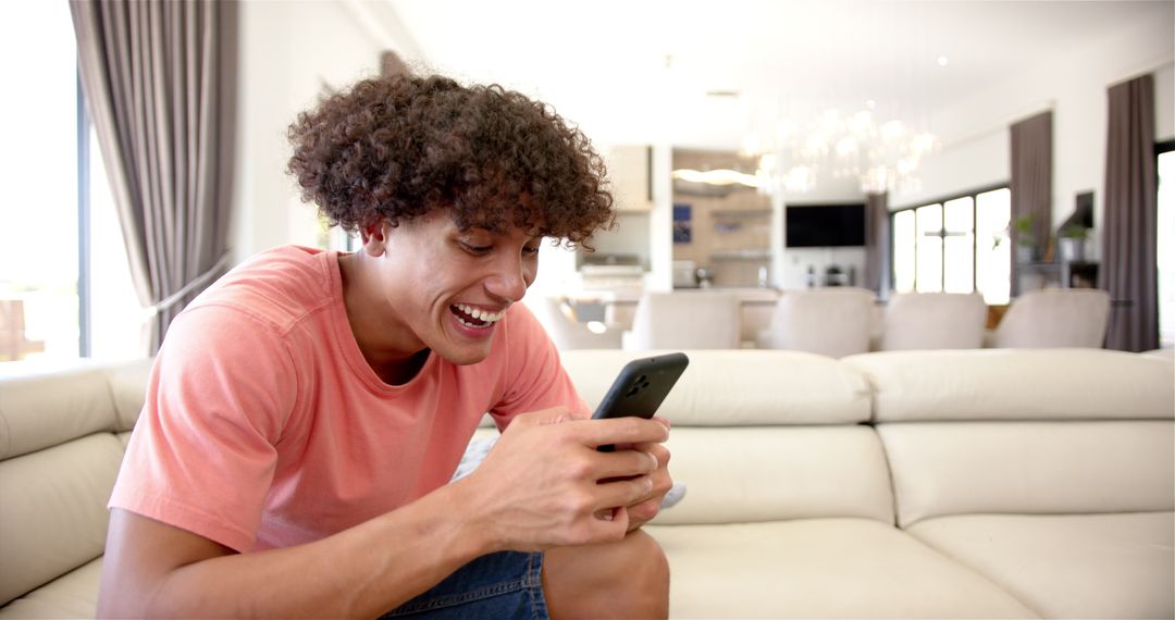 Smiling Man Relaxing on Couch Using Smartphone in Modern Living Room