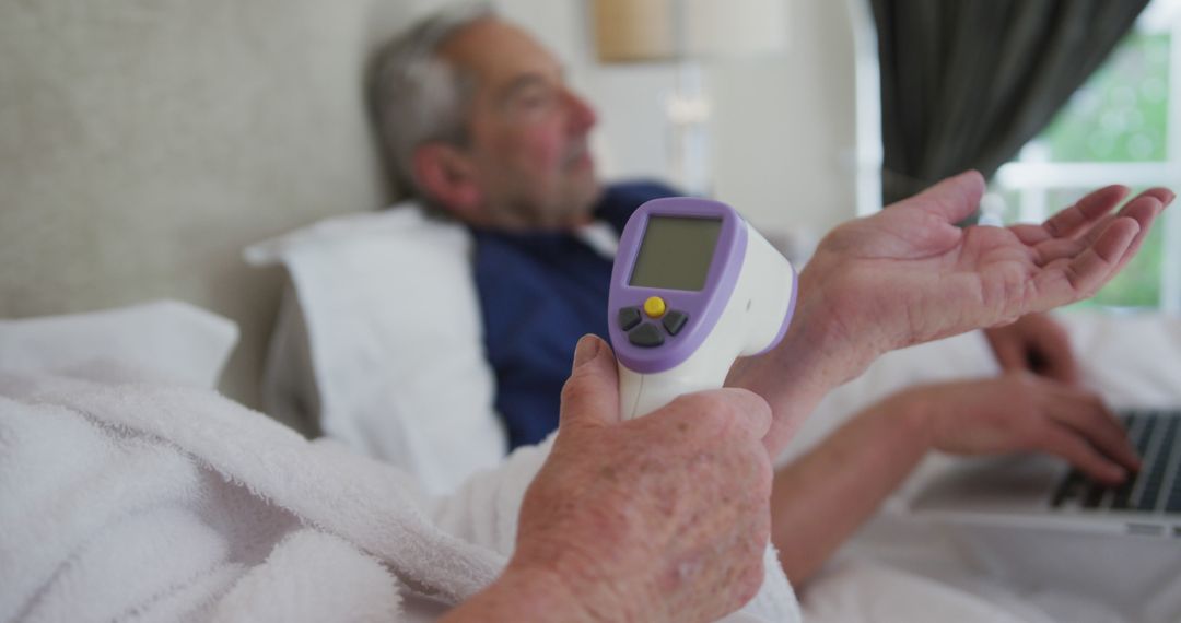 Senior Patient Checked by Thermometer While Typing on Laptop - Free Images, Stock Photos and Pictures on Pikwizard.com