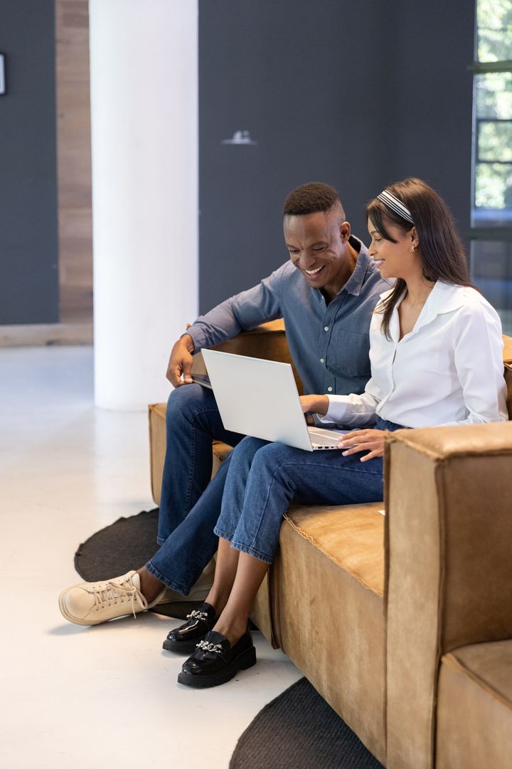 Diverse Colleagues Collaborating in Modern Office Lounge with Laptop