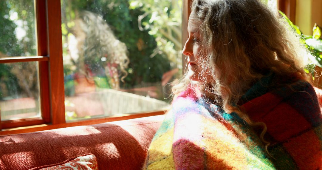 Woman Wrapped in Colorful Blanket Enjoying Tranquil Afternoon by Window - Free Images, Stock Photos and Pictures on Pikwizard.com