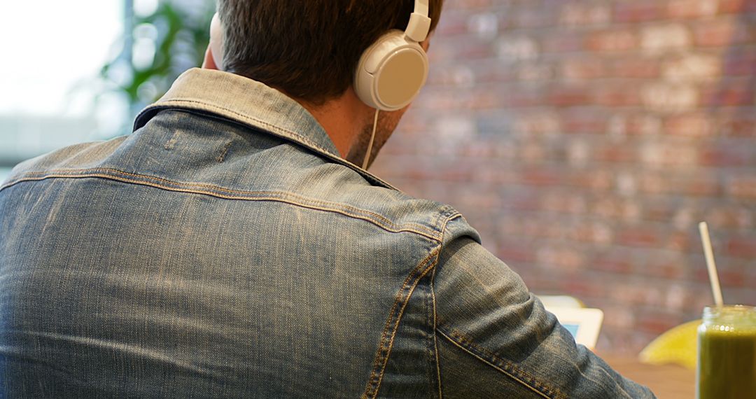 Man Listening to Music with Headphones in Urban Cafe - Free Images, Stock Photos and Pictures on Pikwizard.com