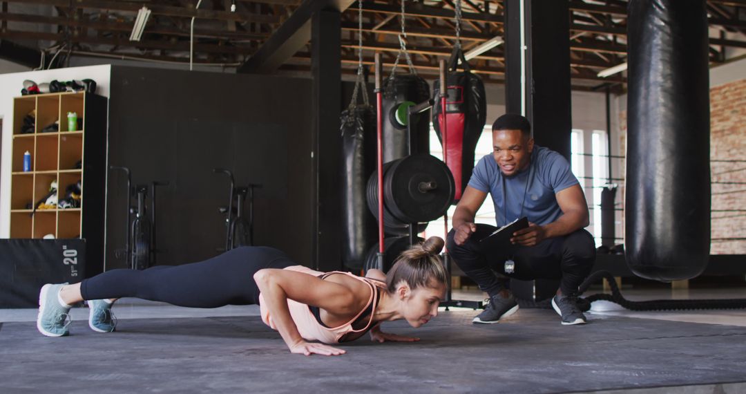 Female athlete doing push-ups under trainer's guidance - Free Images, Stock Photos and Pictures on Pikwizard.com