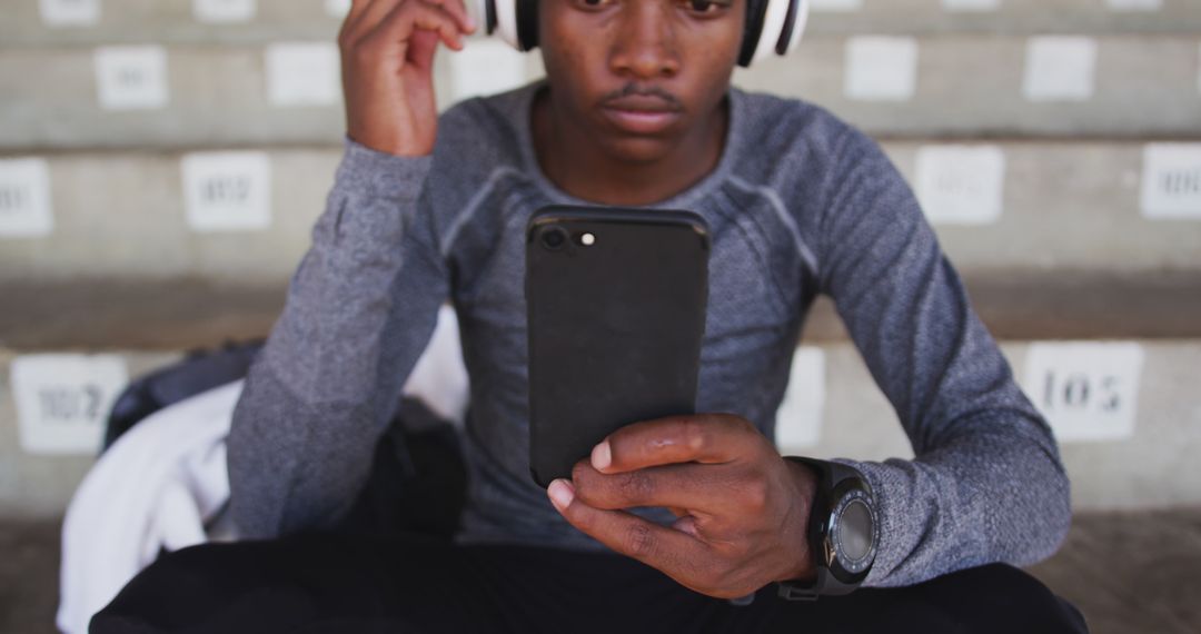 Young Man Wearing Headphones Using Smartphone Outdoors - Free Images, Stock Photos and Pictures on Pikwizard.com