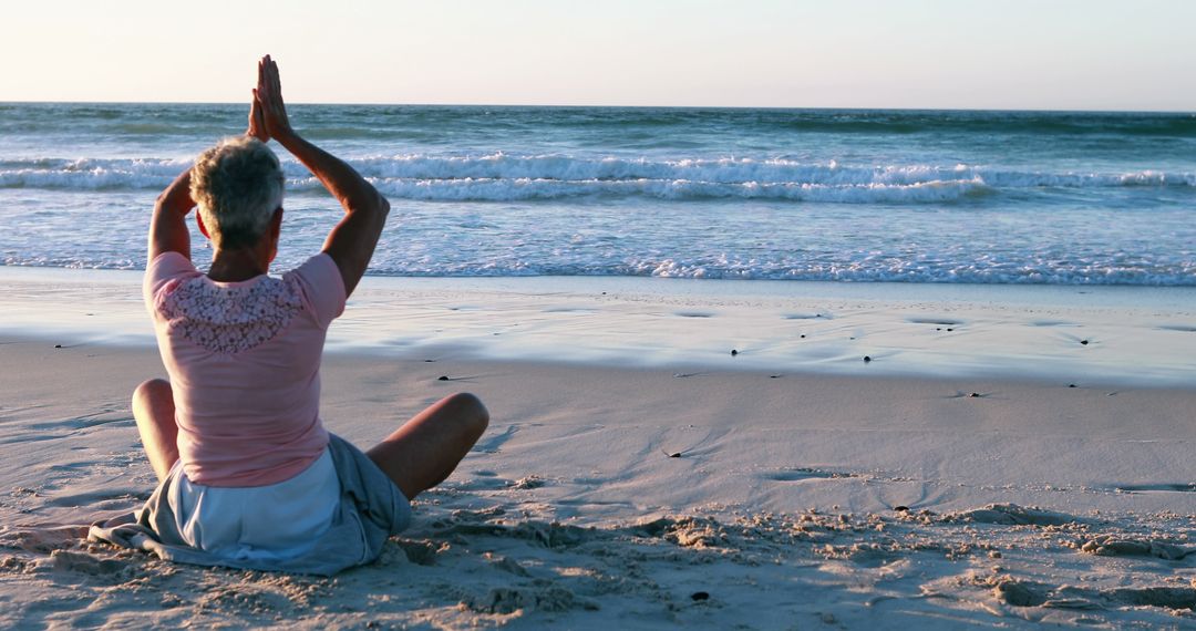 A senior woman practices yoga on a serene beach at sunset, with copy space - Free Images, Stock Photos and Pictures on Pikwizard.com