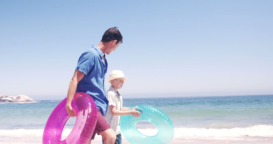 Father and Son Enjoying a Day at the Beach with Inflatable Tubes - Free Images, Stock Photos and Pictures on Pikwizard.com