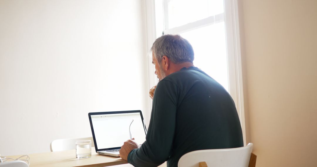 Middle-aged Man Working from Home on Laptop at Dining Table - Free Images, Stock Photos and Pictures on Pikwizard.com